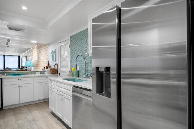 kitchen with stainless steel appliances, a sink, visible vents, white cabinetry, and light wood-style floors