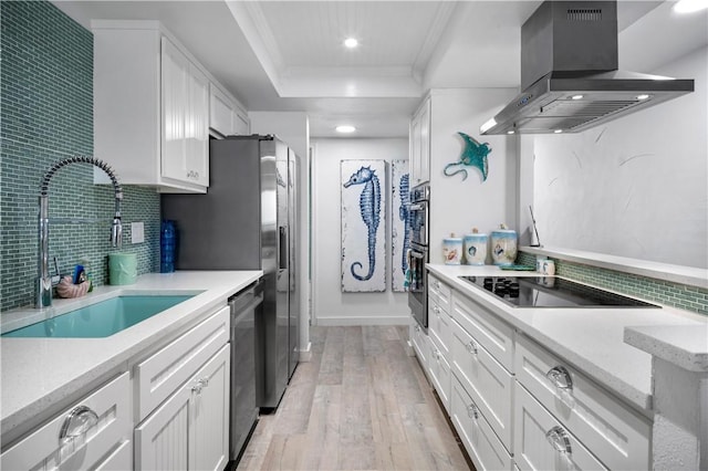 kitchen with appliances with stainless steel finishes, white cabinets, island exhaust hood, and a sink