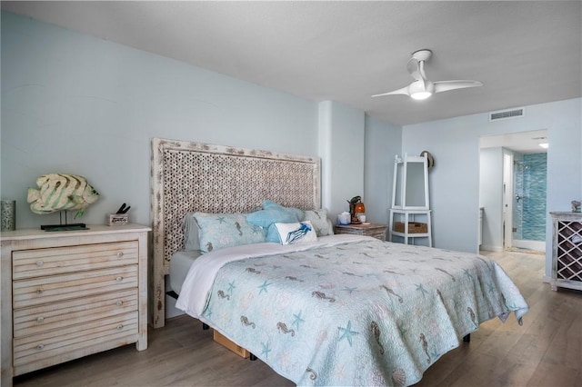 bedroom featuring wood finished floors, visible vents, and a ceiling fan