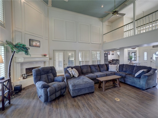 living room featuring crown molding, hardwood / wood-style floors, ceiling fan, and a towering ceiling