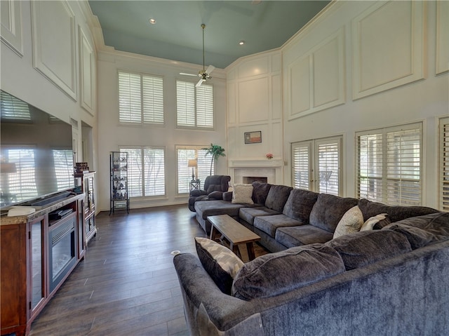 living room with a wealth of natural light, ceiling fan, a high ceiling, and dark hardwood / wood-style flooring