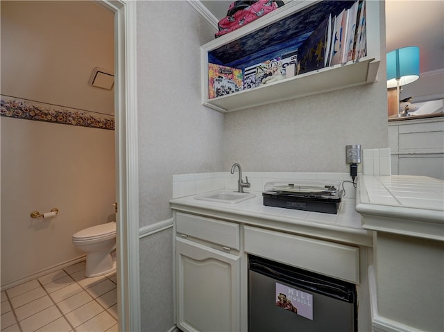 bathroom with toilet, vanity, tile patterned flooring, and crown molding