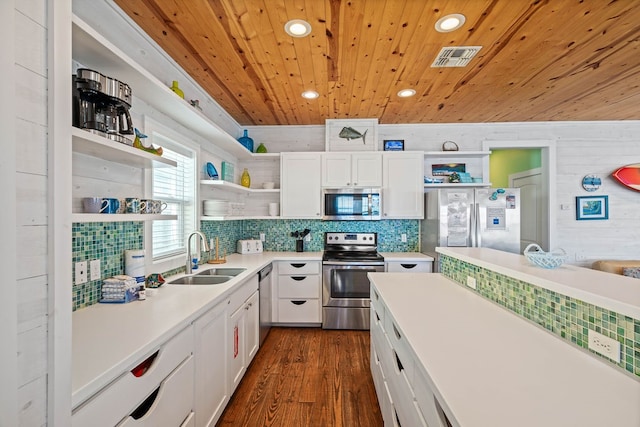 kitchen featuring appliances with stainless steel finishes, white cabinetry, wooden walls, and sink