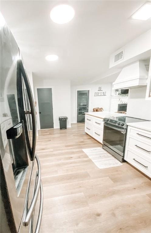 1801 Clare Dr, Alice, TX 78332 - kitchen featuring appliances with stainless steel finishes, custom exhaust hood, white cabinetry, light wood-style flooring, and light countertops