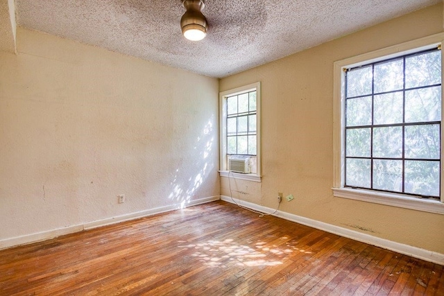 unfurnished room with hardwood / wood-style flooring, a textured ceiling, and cooling unit