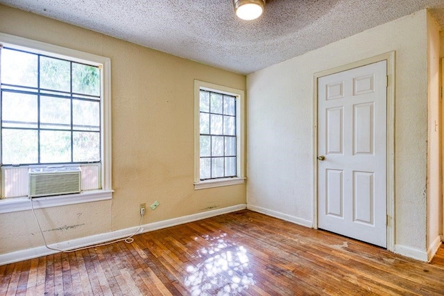 unfurnished room featuring a textured ceiling, cooling unit, and hardwood / wood-style flooring