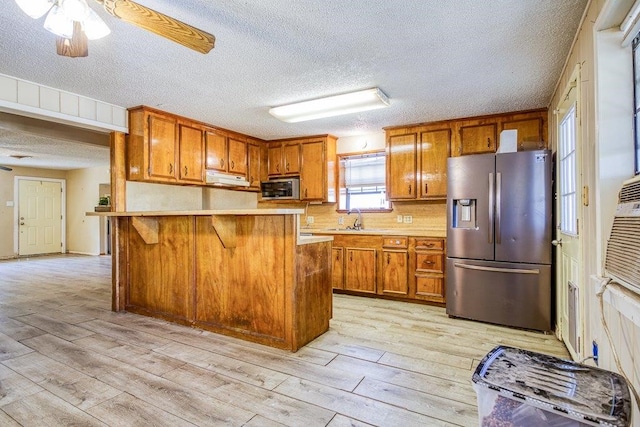 kitchen with light hardwood / wood-style flooring, a textured ceiling, ceiling fan, and stainless steel appliances