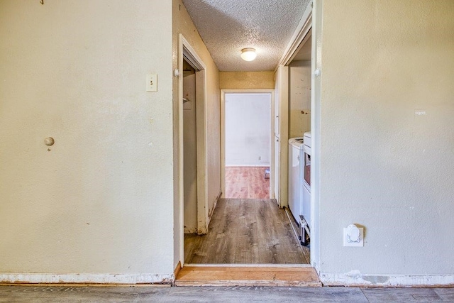 hallway with washing machine and clothes dryer, wood-type flooring, and a textured ceiling