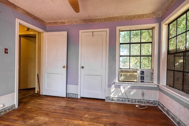 unfurnished bedroom with dark wood-type flooring, cooling unit, a textured ceiling, and ceiling fan