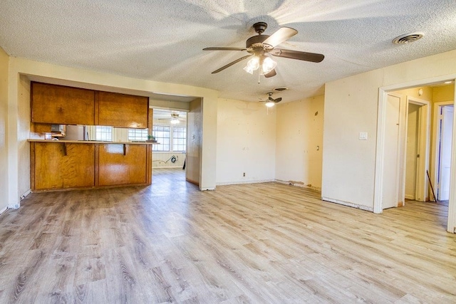 kitchen featuring kitchen peninsula, light hardwood / wood-style floors, a textured ceiling, and ceiling fan