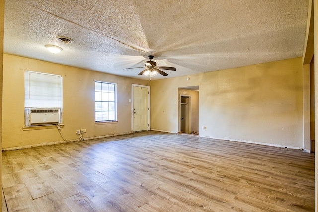 spare room with light hardwood / wood-style flooring, cooling unit, a textured ceiling, and ceiling fan