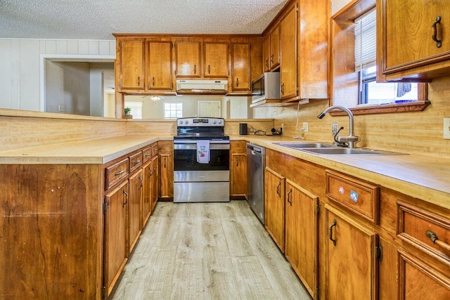 kitchen featuring a textured ceiling, appliances with stainless steel finishes, sink, and light hardwood / wood-style flooring