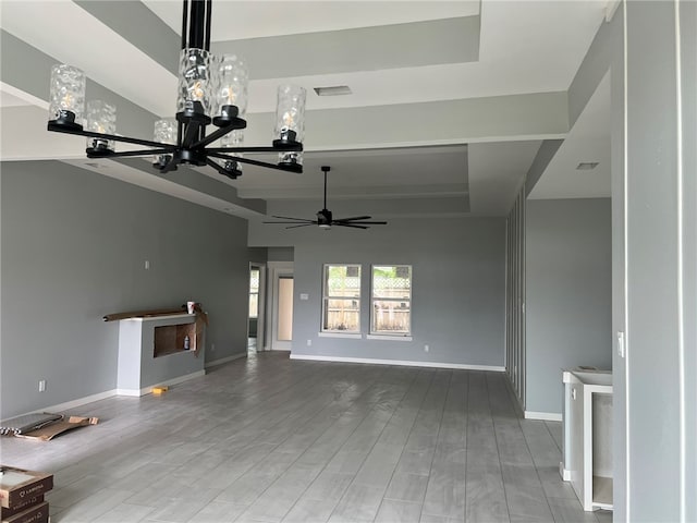 unfurnished living room with wood-type flooring and ceiling fan with notable chandelier