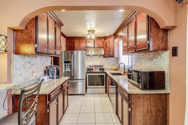 kitchen featuring light tile patterned floors, sink, appliances with stainless steel finishes, light stone counters, and a textured ceiling