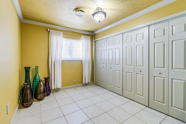 unfurnished bedroom with crown molding, a closet, light tile patterned flooring, and a textured ceiling