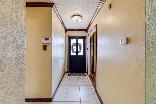 entryway featuring light tile patterned floors, ornamental molding, and a textured ceiling