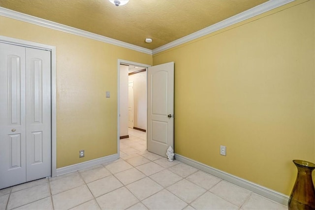 unfurnished bedroom featuring crown molding, a closet, a textured ceiling, and light tile patterned flooring