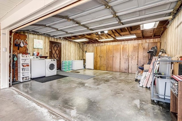 garage with fridge, wooden walls, washing machine and dryer, and white refrigerator