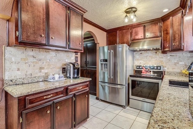 kitchen with light tile patterned floors, stainless steel appliances, tasteful backsplash, light stone countertops, and a textured ceiling