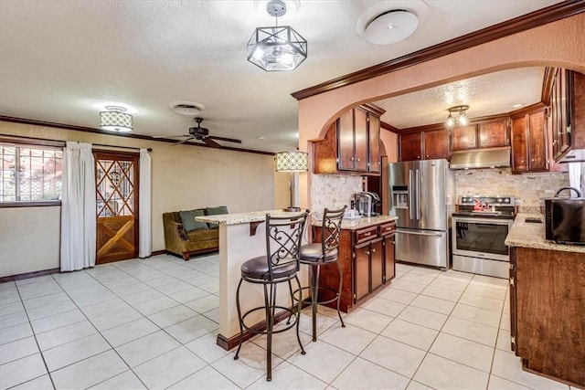 kitchen with ornamental molding, stainless steel appliances, hanging light fixtures, and light tile patterned floors