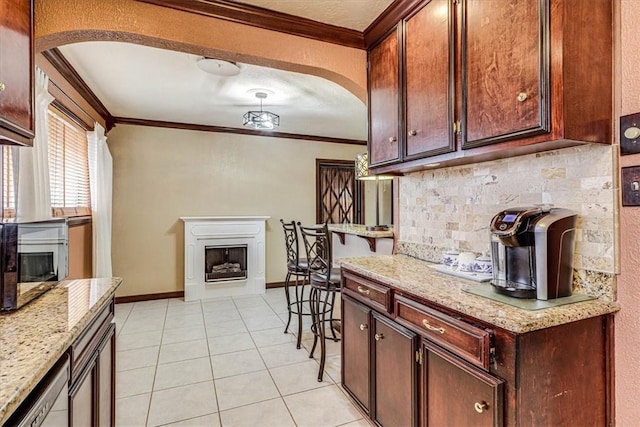 kitchen with light stone counters, crown molding, decorative backsplash, and light tile patterned floors