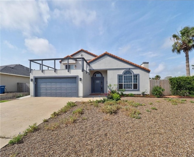 mediterranean / spanish house with a chimney, a garage, fence, concrete driveway, and stucco siding