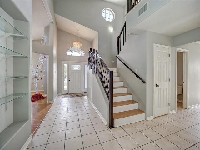 foyer featuring stairs, high vaulted ceiling, visible vents, and light tile patterned floors