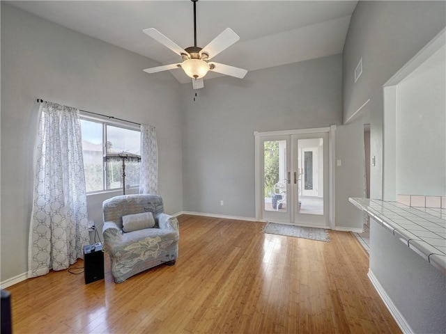 sitting room with a ceiling fan, french doors, visible vents, high vaulted ceiling, and light wood finished floors
