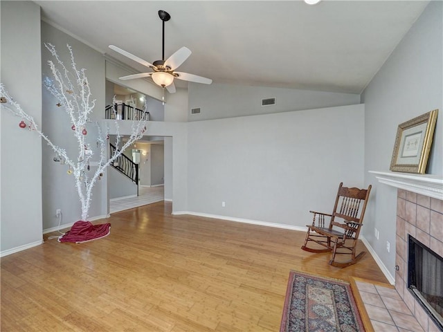 unfurnished living room featuring ceiling fan, stairs, wood finished floors, a tile fireplace, and visible vents