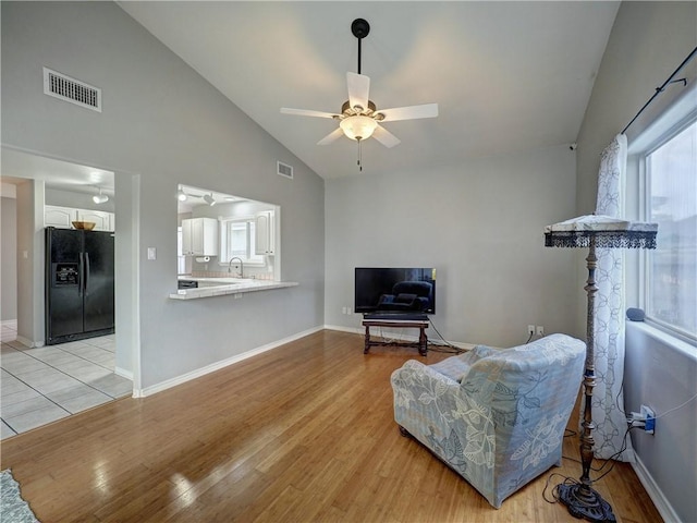 living room with high vaulted ceiling, ceiling fan, light wood-style flooring, and visible vents