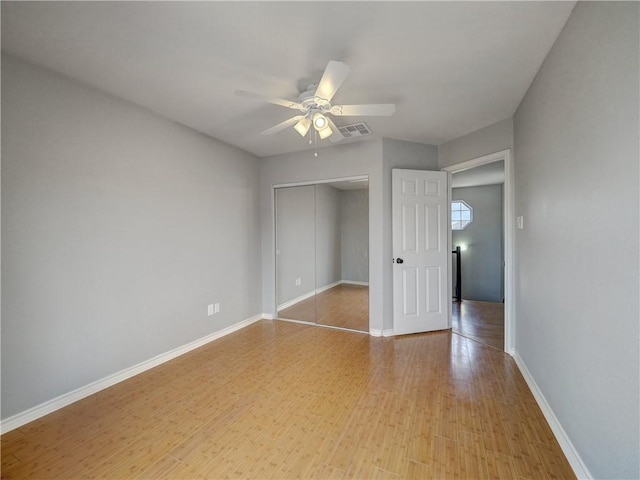 unfurnished bedroom with ceiling fan, light wood finished floors, baseboards, visible vents, and a closet