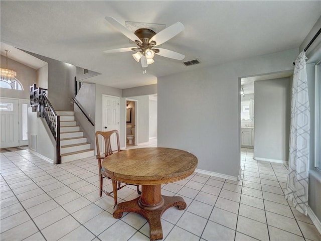 dining room featuring ceiling fan with notable chandelier, stairs, light tile patterned flooring, and visible vents