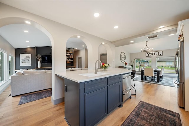 kitchen featuring light wood-style flooring, appliances with stainless steel finishes, open floor plan, and a sink