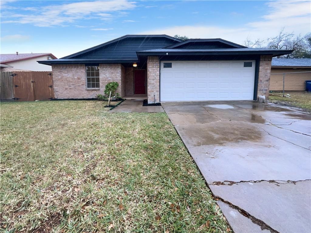 ranch-style house featuring fence, a garage, concrete driveway, a front yard, and brick siding