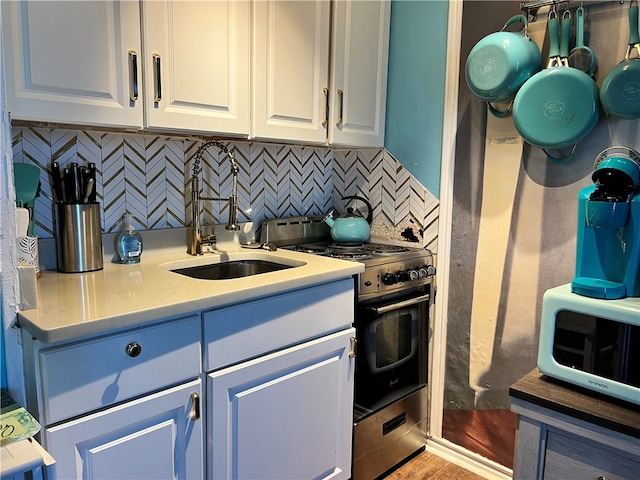 kitchen with white cabinets, decorative backsplash, sink, and range with gas stovetop