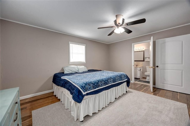 bedroom with ceiling fan, light wood finished floors, ensuite bath, and baseboards