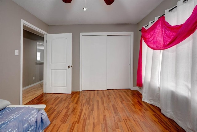 bedroom with a ceiling fan, a closet, baseboards, and light wood finished floors