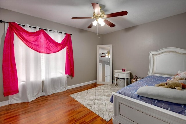 bedroom with wood finished floors, a ceiling fan, and baseboards