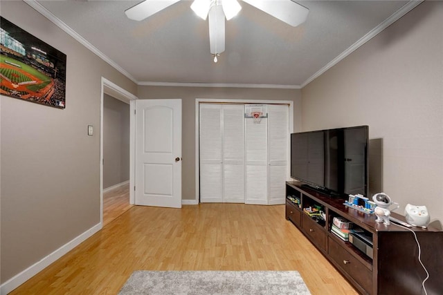 living area featuring light wood finished floors, a ceiling fan, baseboards, and crown molding