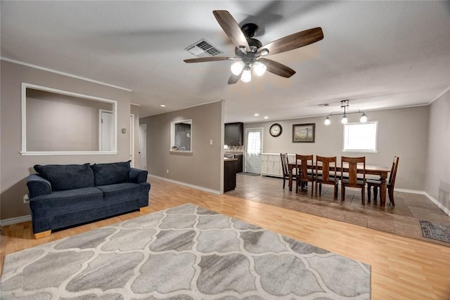 living area with light wood-style floors, baseboards, visible vents, and a ceiling fan