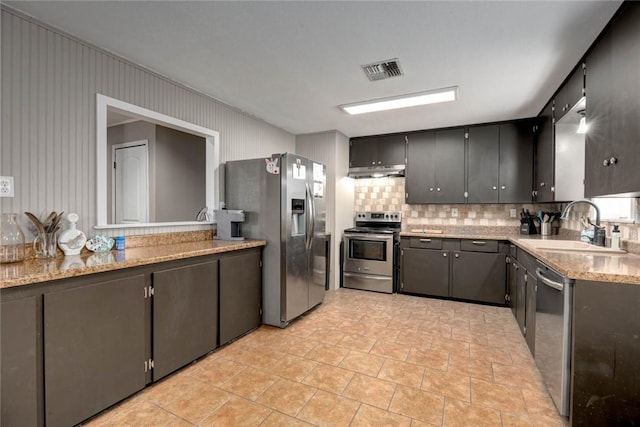 kitchen with tasteful backsplash, visible vents, stainless steel appliances, under cabinet range hood, and a sink