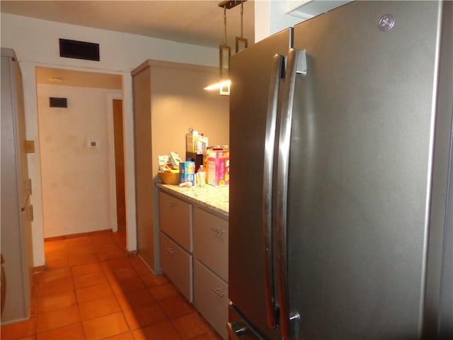kitchen with freestanding refrigerator, visible vents, and light tile patterned floors