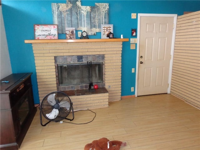 living room featuring a brick fireplace and wood finished floors