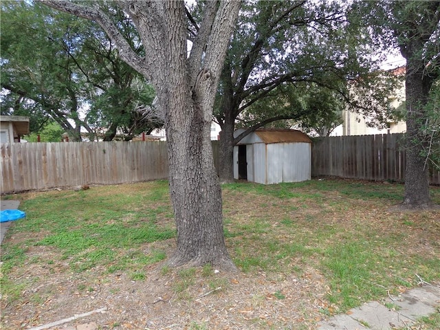 view of yard featuring an outbuilding, a fenced backyard, and a storage unit