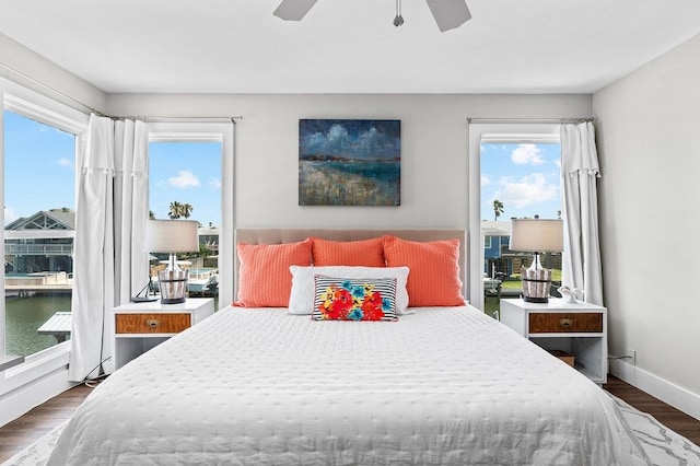 bedroom featuring a water view, dark hardwood / wood-style floors, and ceiling fan