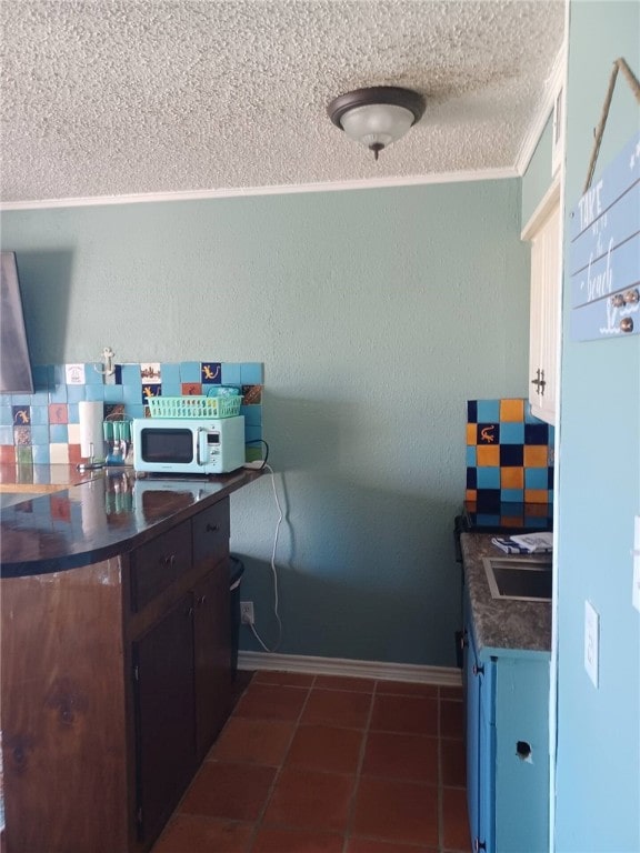 kitchen featuring a textured ceiling, backsplash, crown molding, and sink