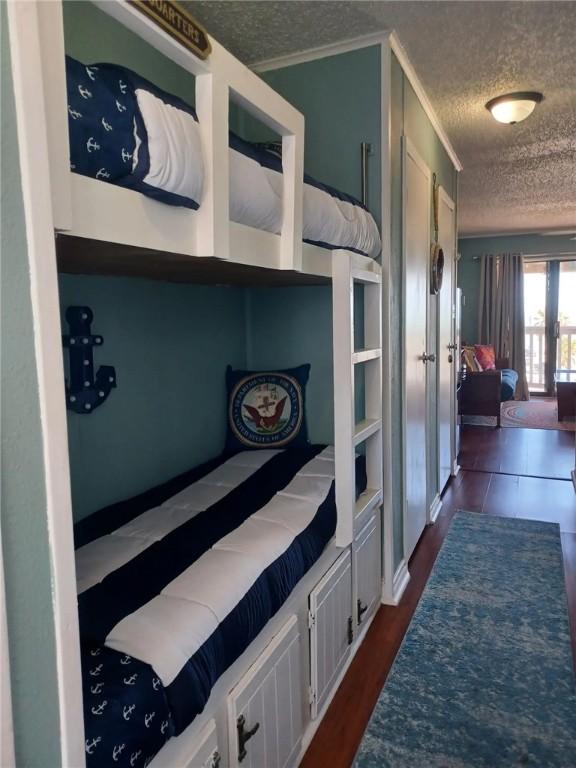 bedroom featuring french doors, dark hardwood / wood-style floors, a textured ceiling, and ornamental molding