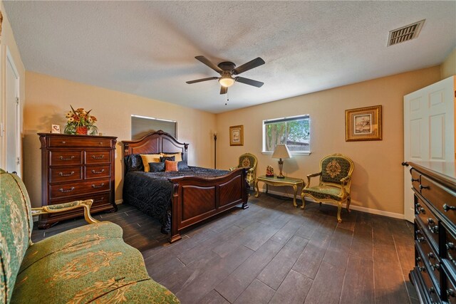 bedroom featuring dark wood-type flooring, ceiling fan, and a textured ceiling