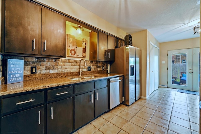 kitchen featuring appliances with stainless steel finishes, tasteful backsplash, light stone counters, and sink