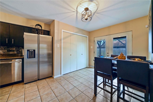 kitchen with appliances with stainless steel finishes, french doors, light tile patterned flooring, and a textured ceiling